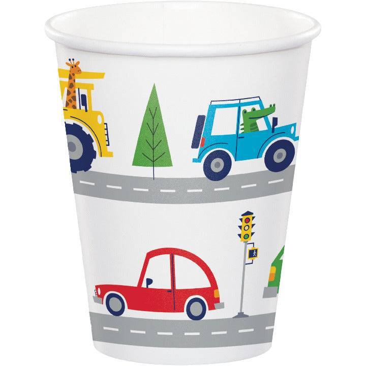 Vaso de papel decorado con ilustraciones de como jeep, auto rojo y camión en una carretera con árboles y señales de tráfico.